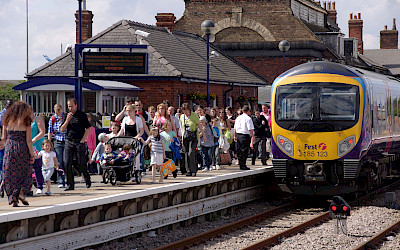 A picture of a train on the tracks with passengers alighting the train.