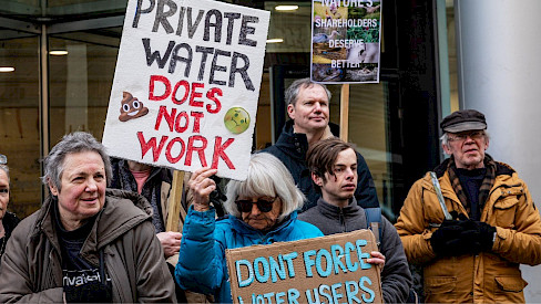Image of campaigners outside the High Court holding signs that say "private water does not work"