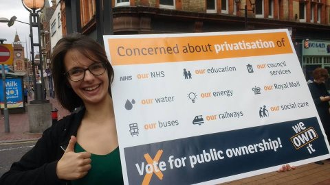 Ellen from the We Own It team with a public ownership poster