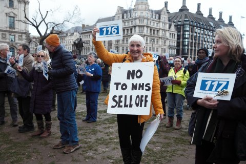 Campaigner with sign that says "No to NHs sell off" - in opposition to NHS privatisation