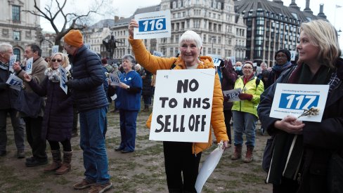 Campaigner with sign that says "No to NHs sell off" - in opposition to NHS privatisation