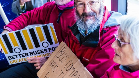 people sitting on a bus holding placards